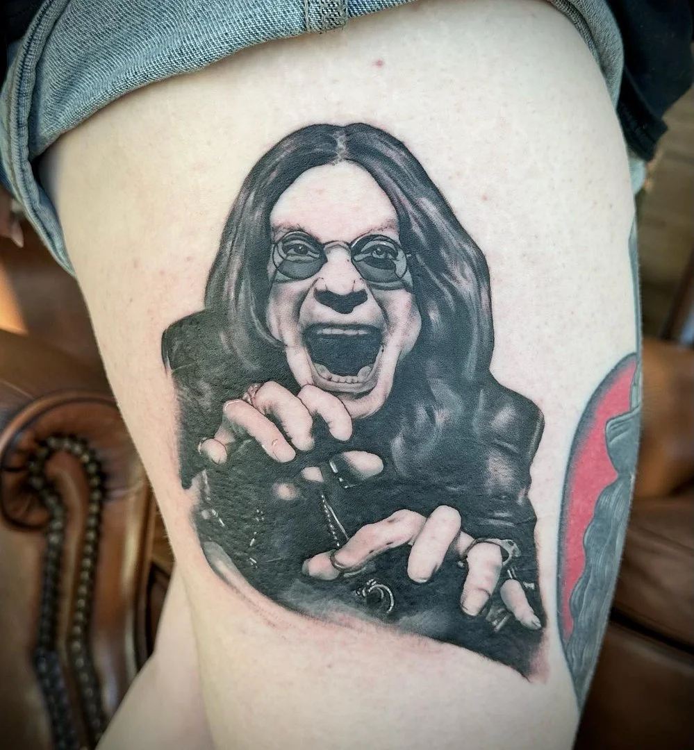 Realistic black-and-grey portrait tattoo on thigh.