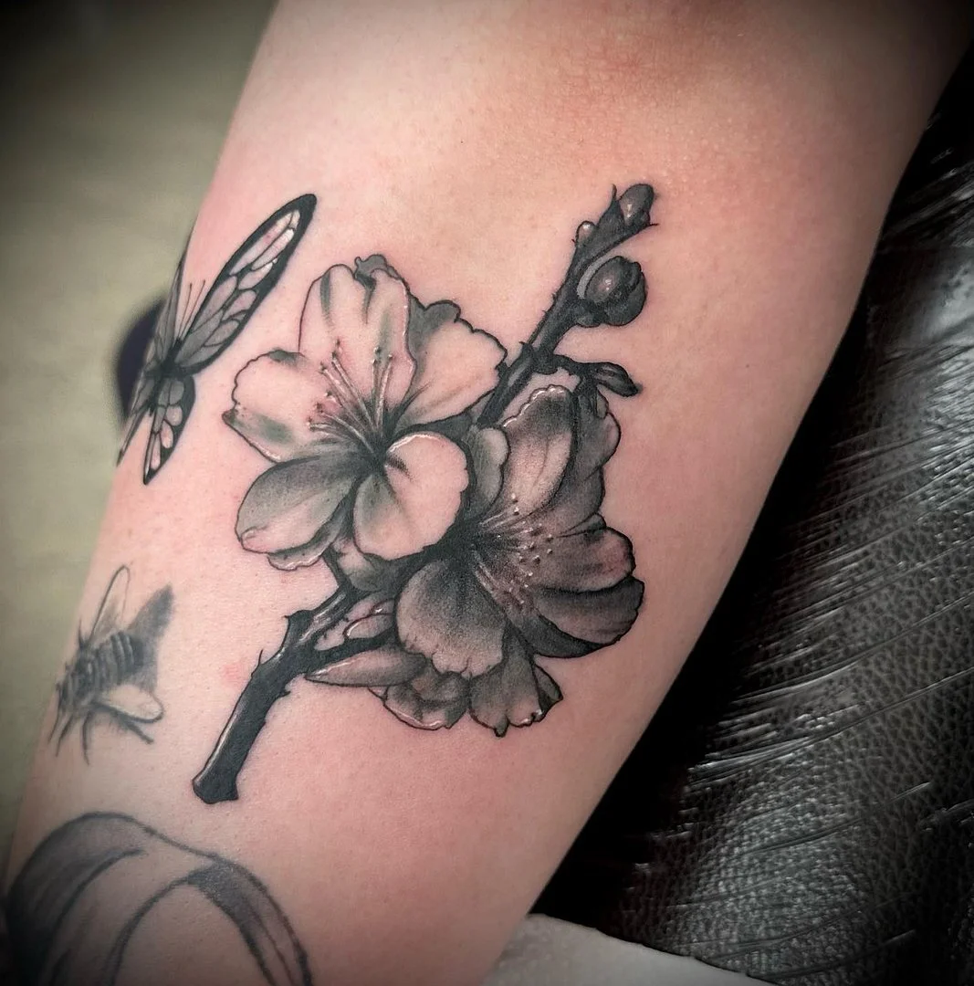 Black-and-grey flower tattoo on forearm.
