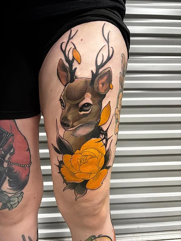 Illustrative deer tattoo with flowers on thigh.