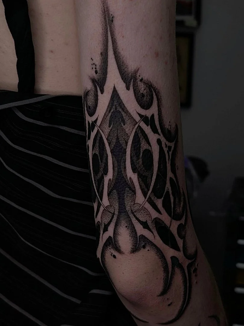Medium-sized tribal tattoo on the arm with bold black lines.