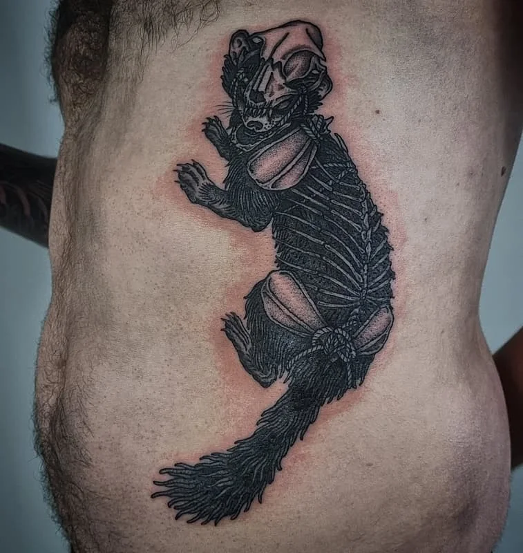 Detailed blackwork tattoo of a skeletonized animal on rib.