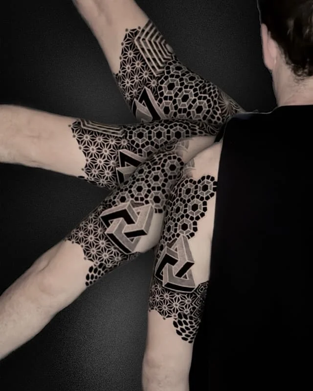Large geometric blackwork tattoo on arm and shoulder.