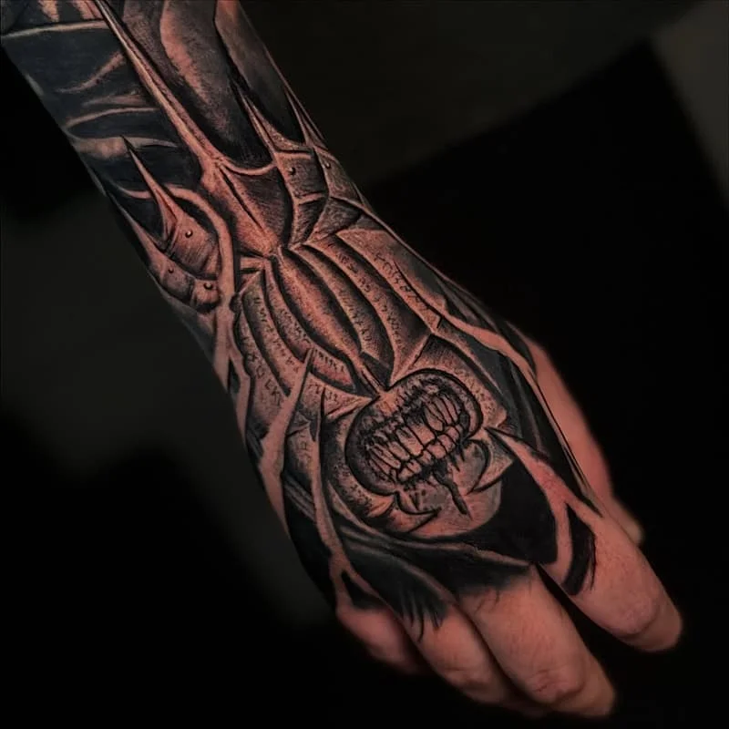 Black and grey biomechanical skull and spider tattoo on hand.