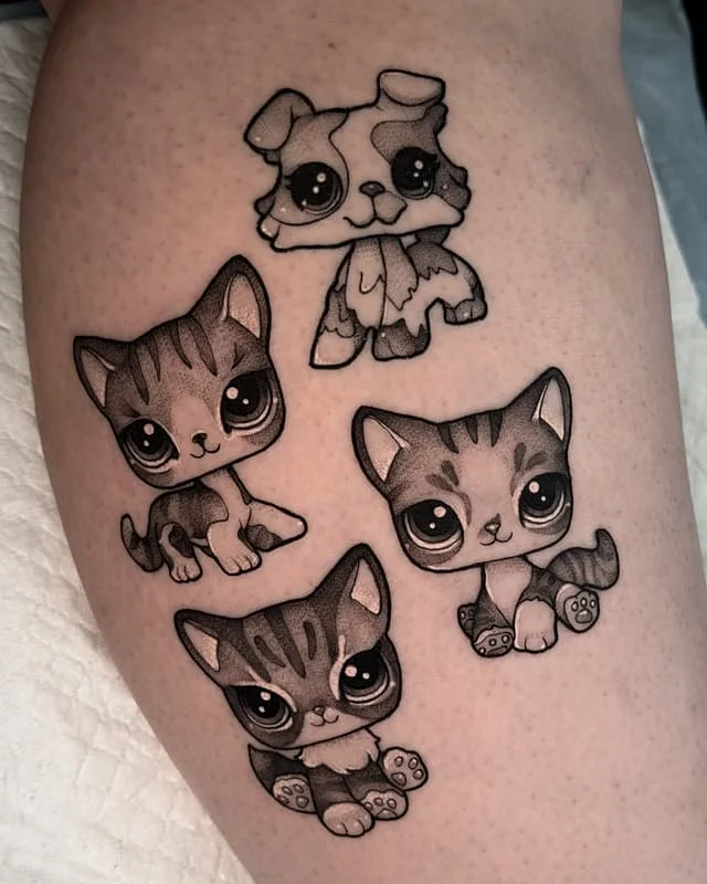 Cute cartoon-style tattoo of kittens and a puppy on thigh.