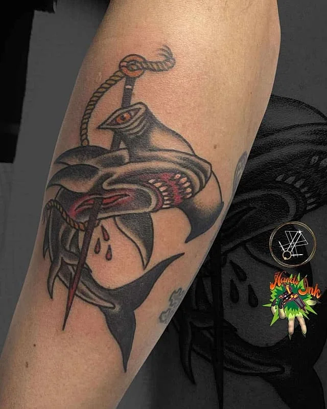 Colorful shark and sword tattoo on arm.