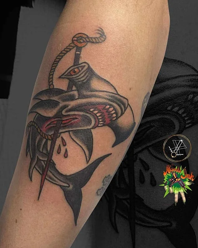 Traditional shark tattoo with a sword on the arm.