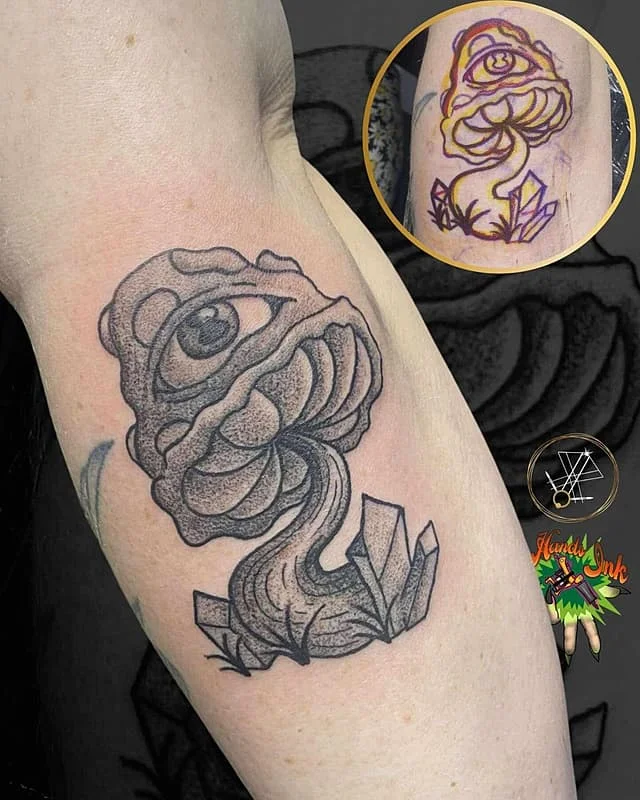 Illustrative tattoo of an eye and mushroom on arm.