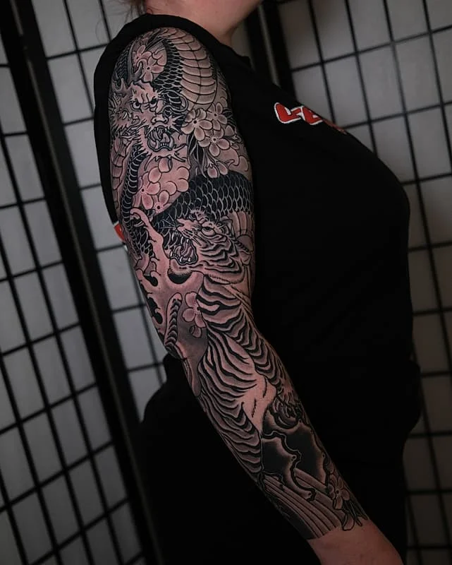 Full-sleeve Japanese tattoo featuring a dragon and tiger.