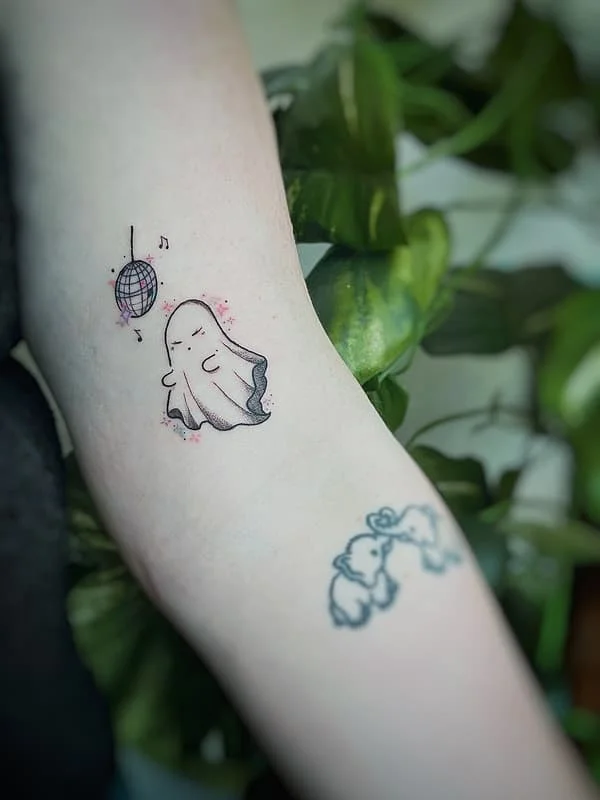 Illustrative ghost tattoo with a disco ball on the arm.