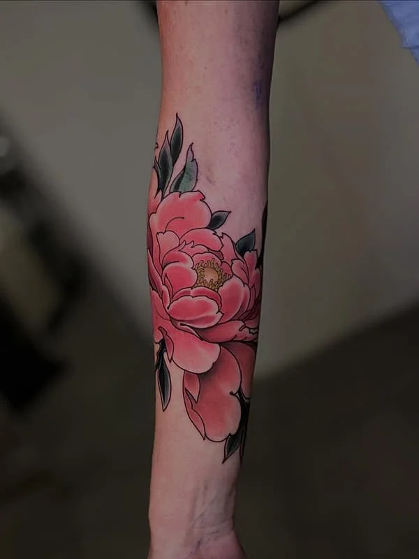 Illustrative peony tattoo on a forearm.