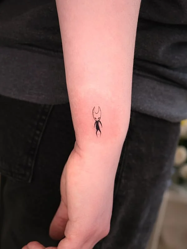 Minimalist crab tattoo on forearm.