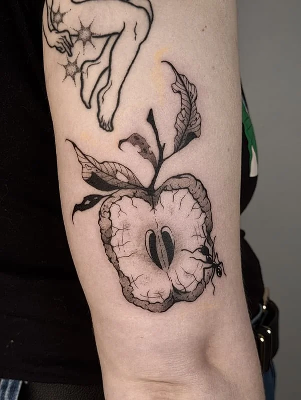 Black and grey apple tattoo with leaves and an ant on forearm.
