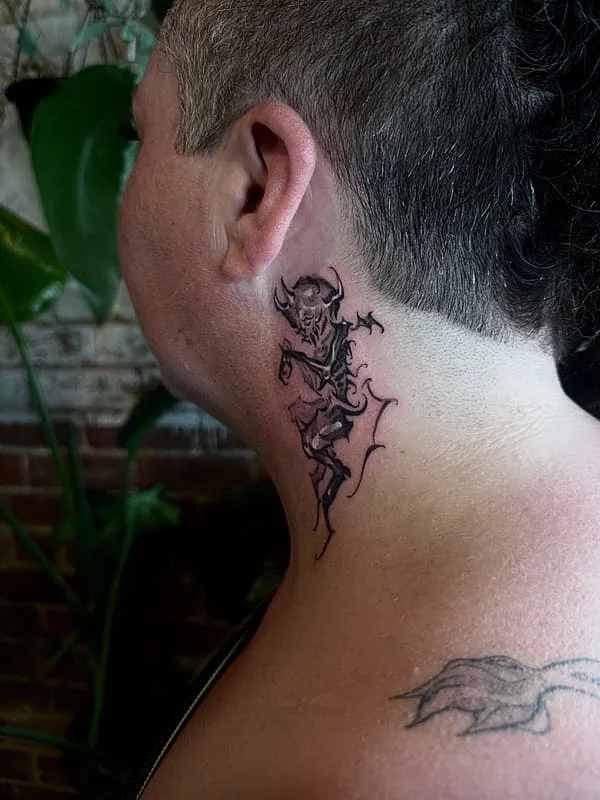 Black-and-grey demon tattoo on neck.