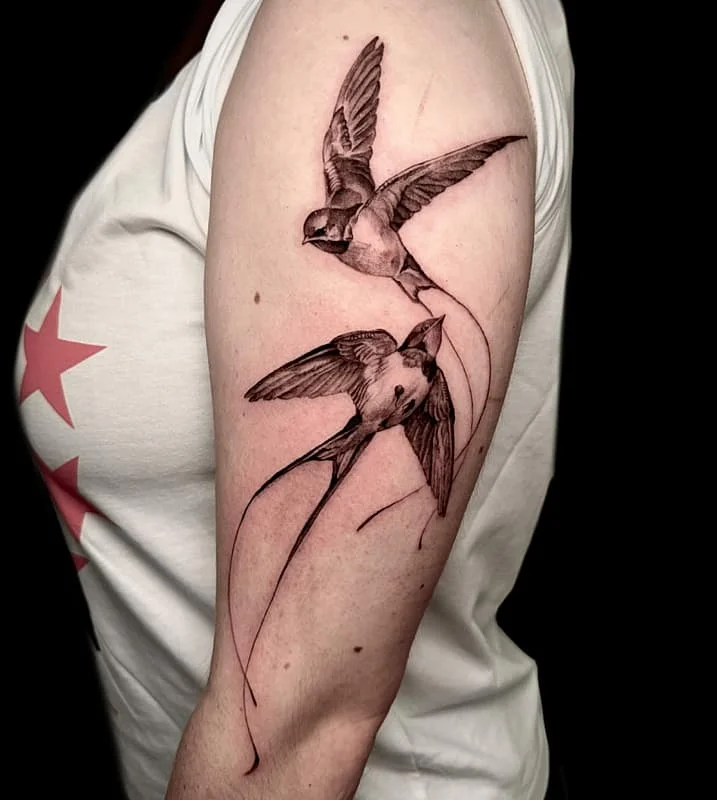 Realistic black-and-grey bird tattoo on arm.