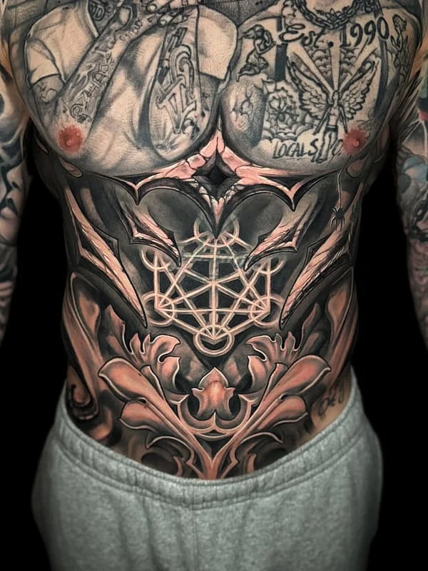 Large black-and-grey geometric tattoo on chest and rib.