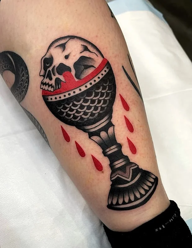 Traditional skull goblet tattoo with blood on arm.
