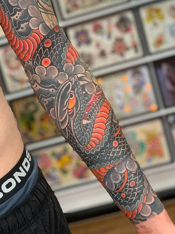 Japanese-style tattoo of koi fish and waves on arm.