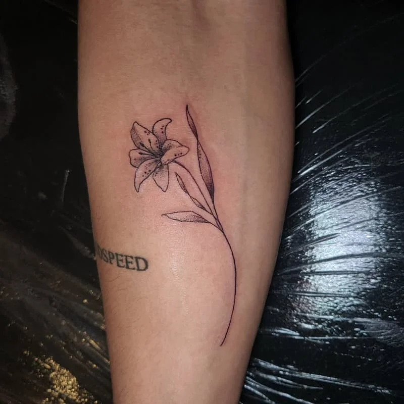 Delicate fine-line flower tattoo on forearm.