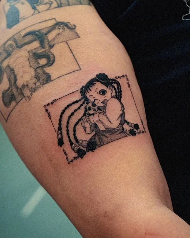 Illustrative tattoo of a girl holding a doll on arm.
