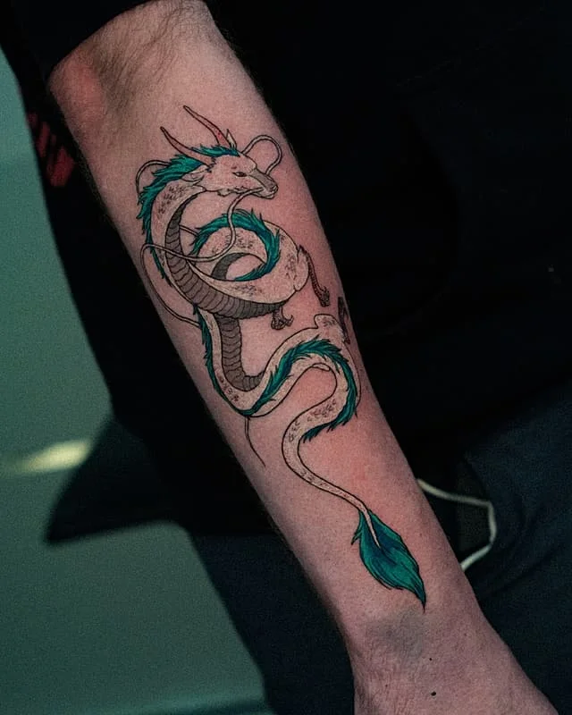 Colorful illustrative dragon tattoo on forearm.