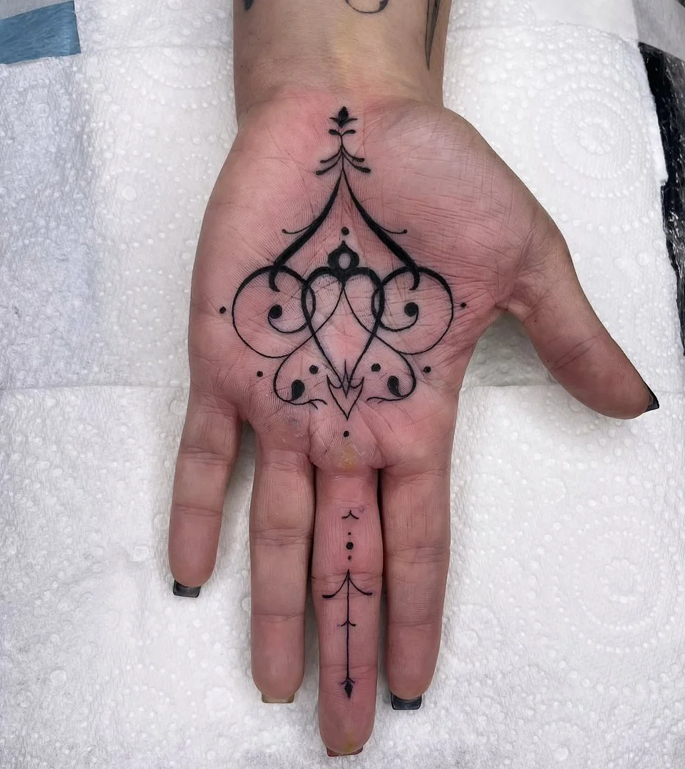 Intricate black geometric tattoo on palm of hand.