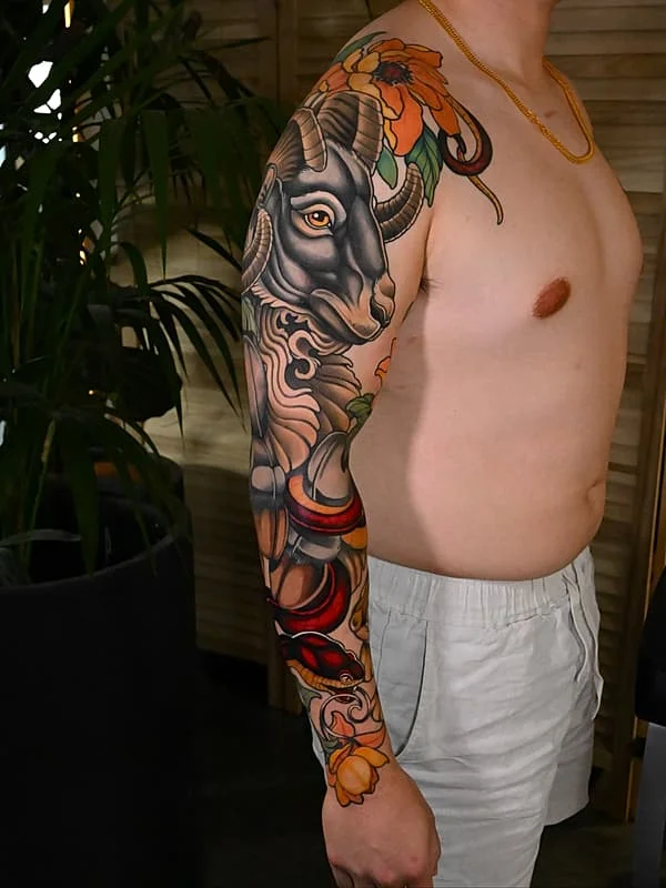 Colorful full-sleeve tattoo of a ram and flowers.