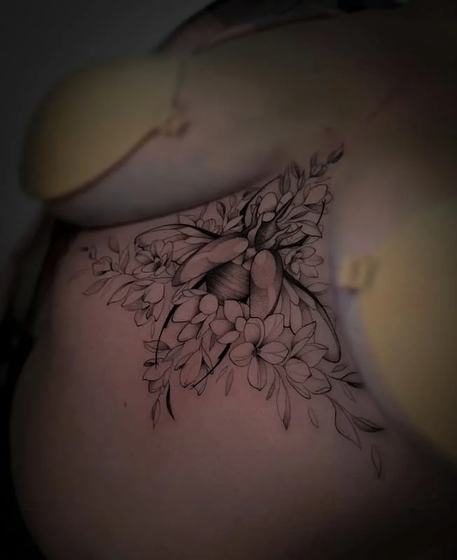 Black-and-grey floral tattoo with insect on chest.