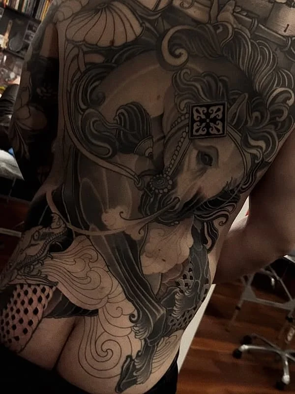 Large illustrative black-grey tattoo on a person's back.
