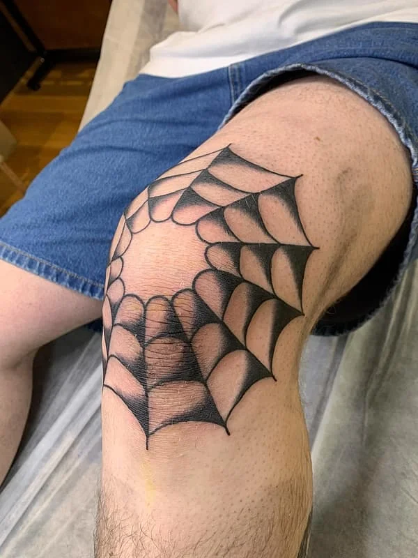 Black spider web tattoo on a knee.