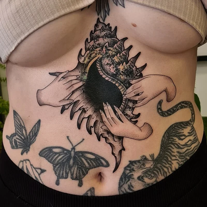 Blackwork tattoo of hands holding an abstract shell on rib.
