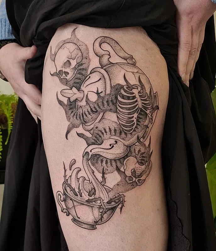 Black and grey thigh tattoo featuring skulls and detail work