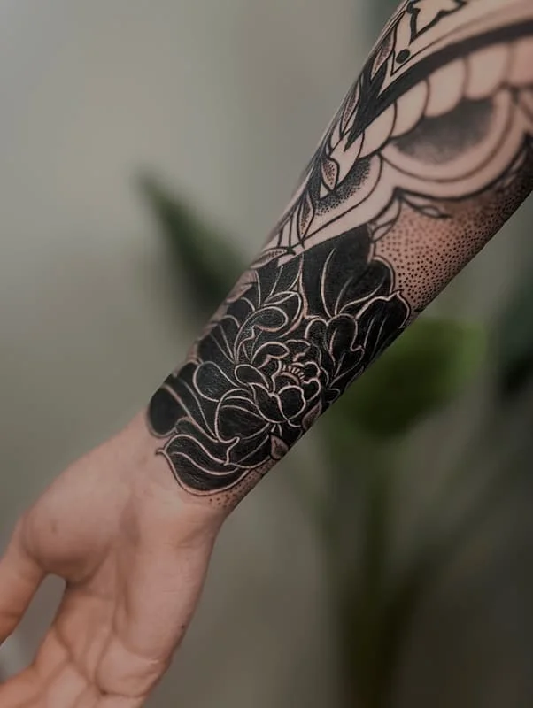 Blackwork floral tattoo on forearm.
