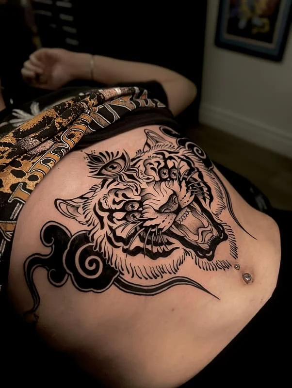 Large black-and-grey tiger tattoo on chest.