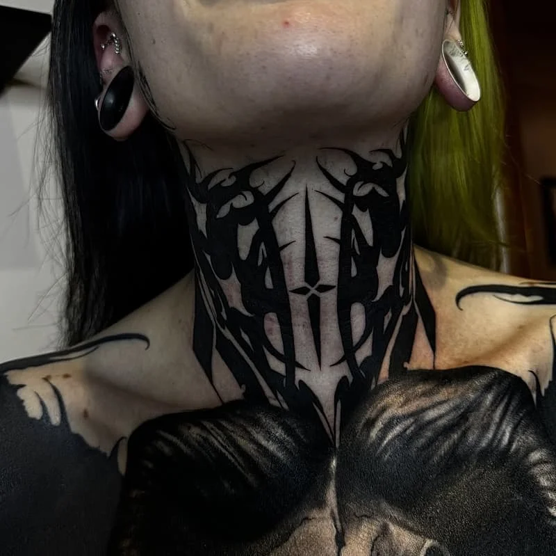 Intricate blackwork tattoo on neck and chest.