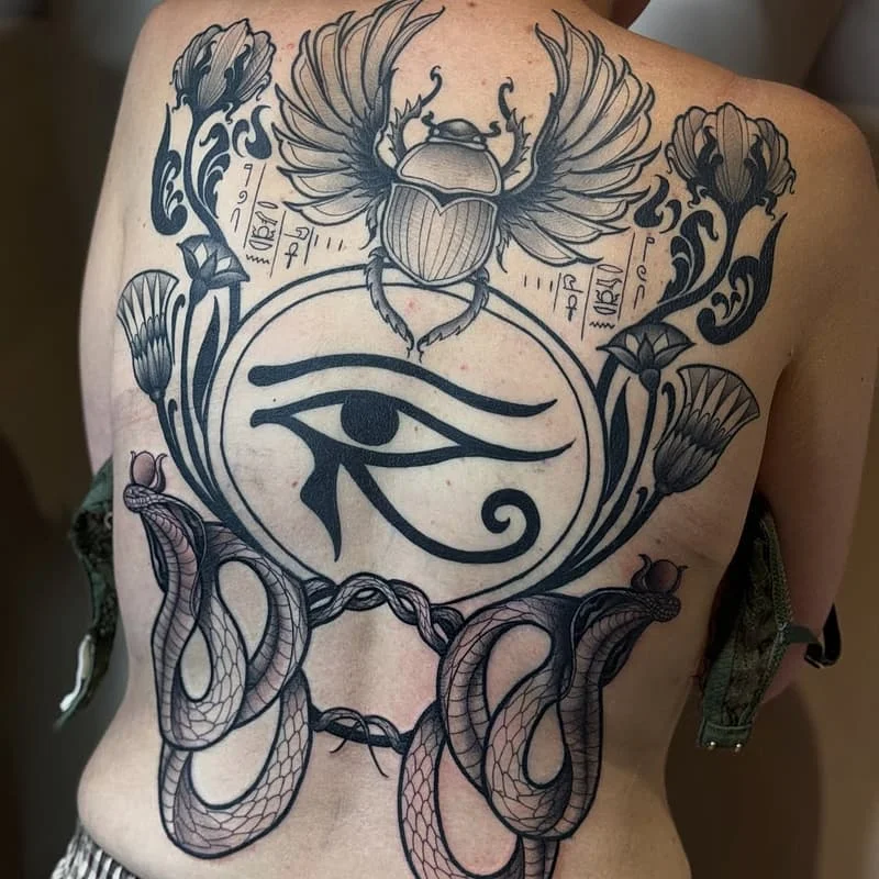 Large blackwork tattoo featuring Eye of Horus and scarab on back.