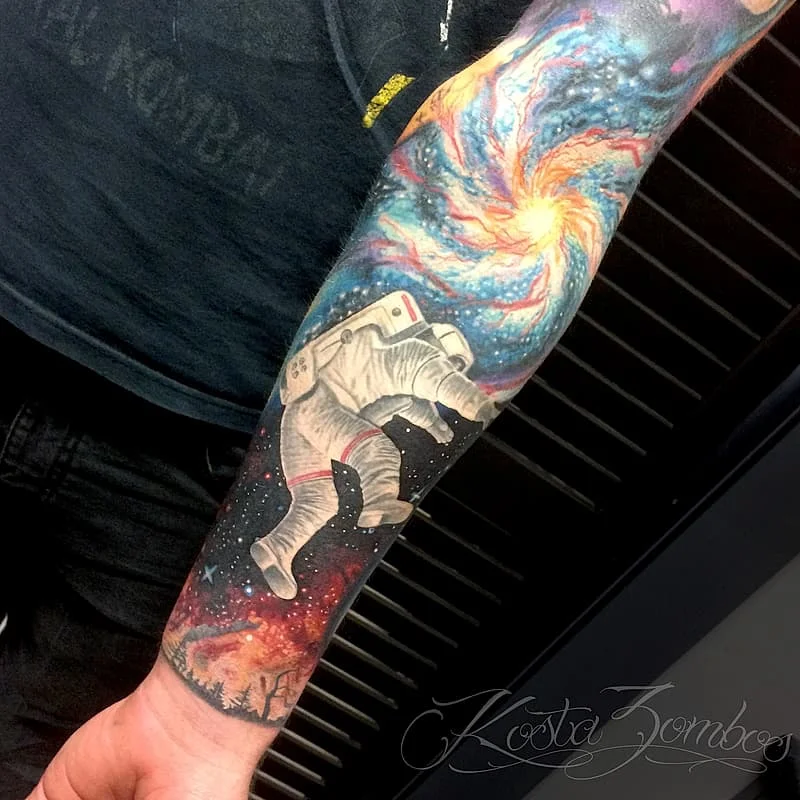 Large colorful astronaut tattoo on forearm with galaxy background.