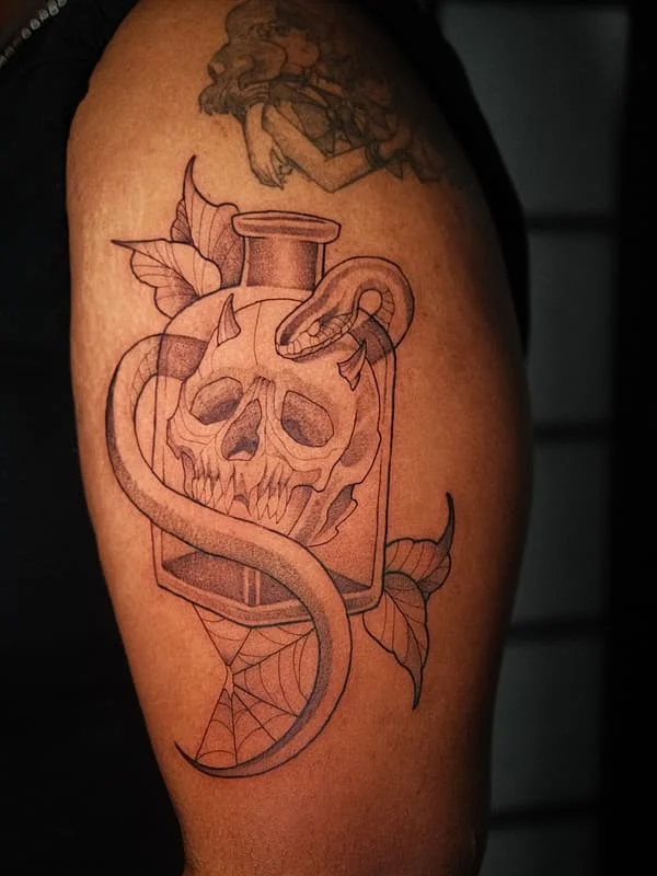 Blackwork tattoo of a skull and snake on bicep.