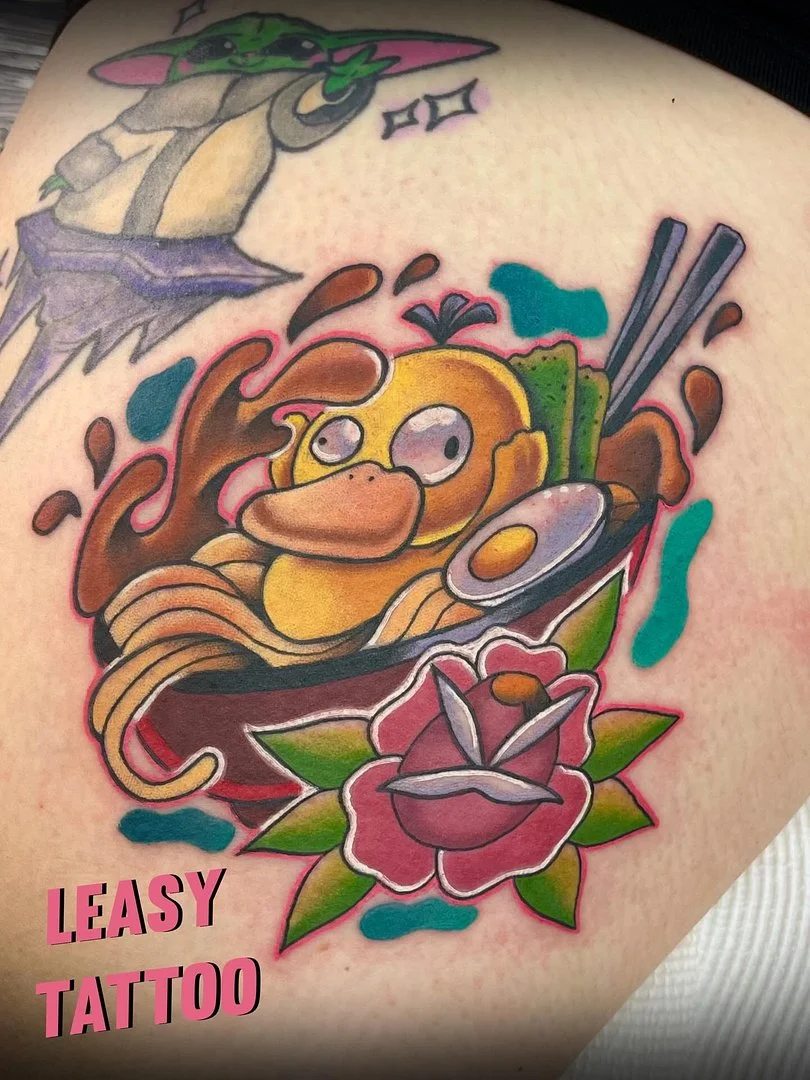 Colorful cartoon character tattoo on thigh with noodles and rose.