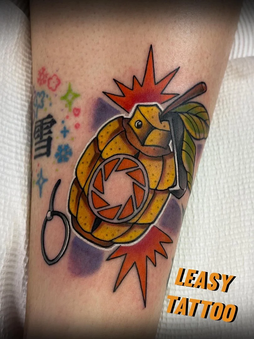 Colorful grenade tattoo with explosion and leaf on forearm.