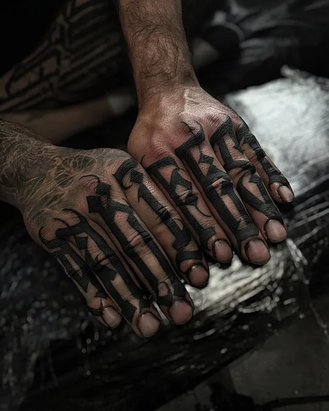 Bold black lettering tattoo on hands.