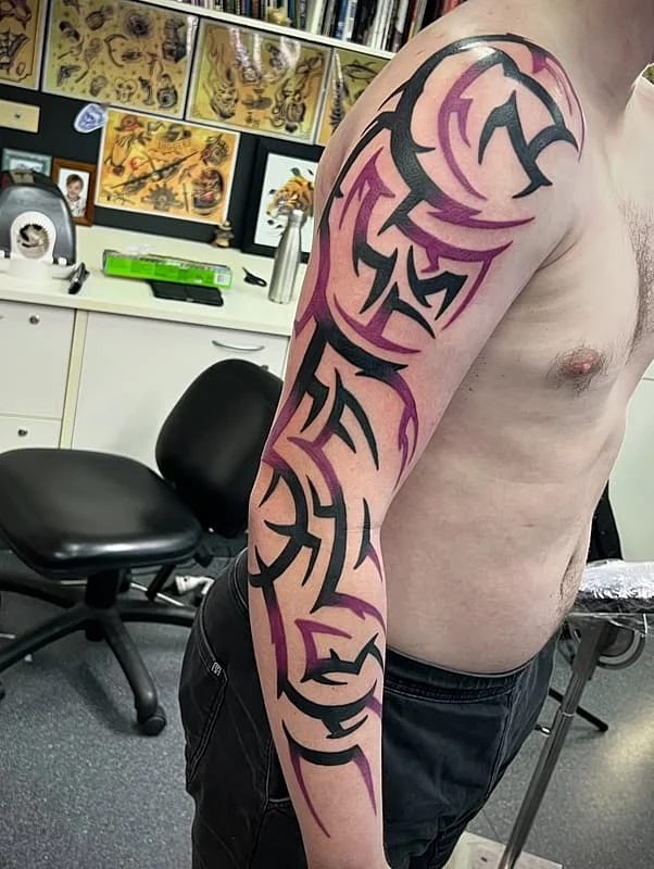 Large tribal tattoo on a male's arm with bold lines.