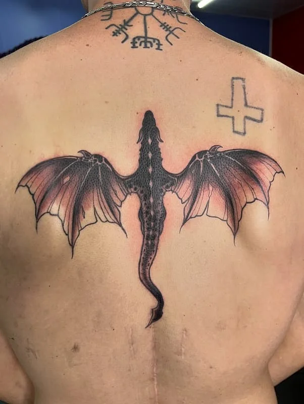 Large dragon tattoo with wings on a man's back.