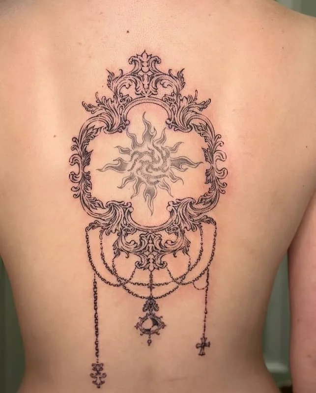 Large ornate blackwork tattoo on a woman's back.