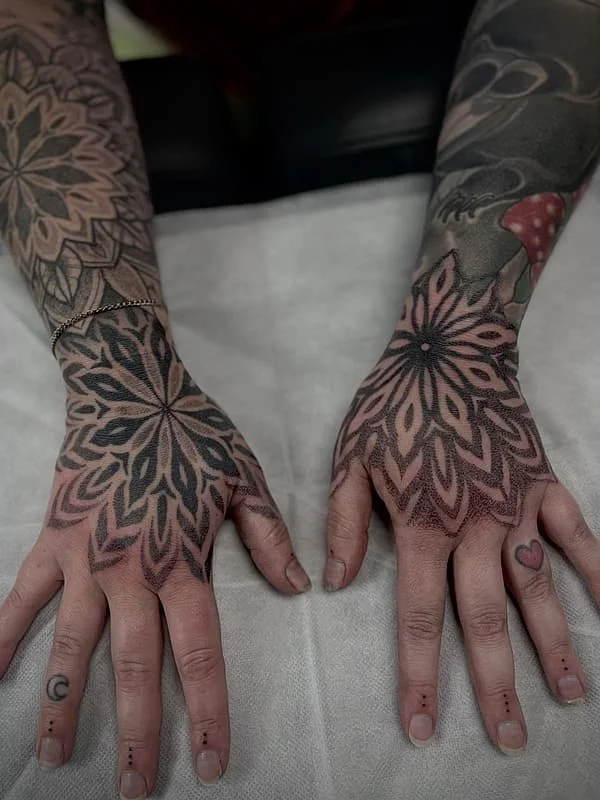Intricate mandala tattoos on both hands.
