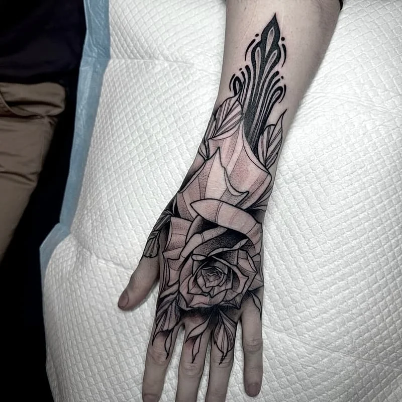 Black-and-grey rose tattoo on hand and forearm.
