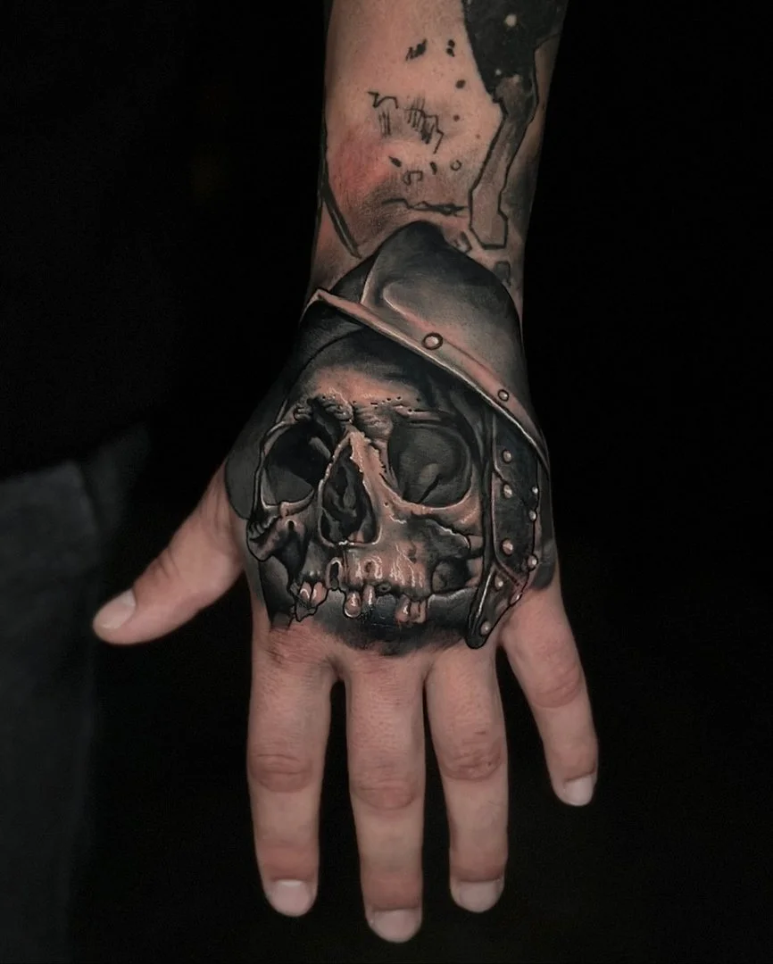 Detailed black-and-grey skull tattoo on a hand.