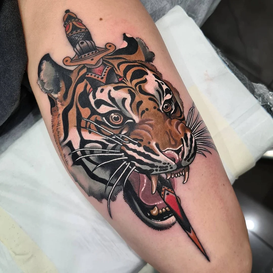 Large illustrative tiger tattoo with a sword on arm.