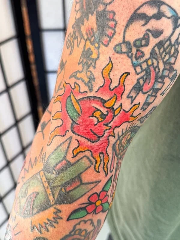 Vibrant traditional tattoo of a rose and flames on an arm.