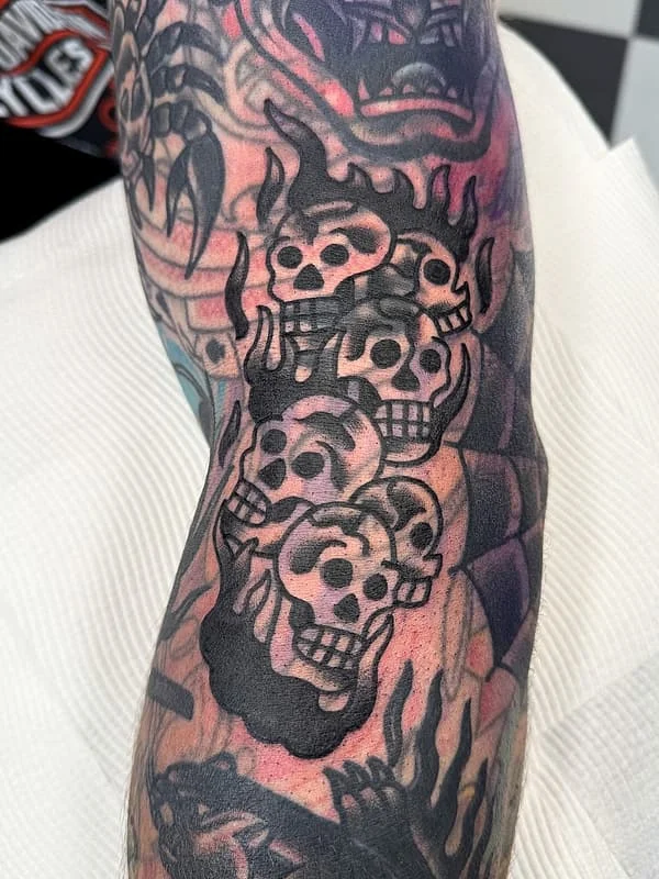 Blackwork forearm tattoo featuring skulls and flames