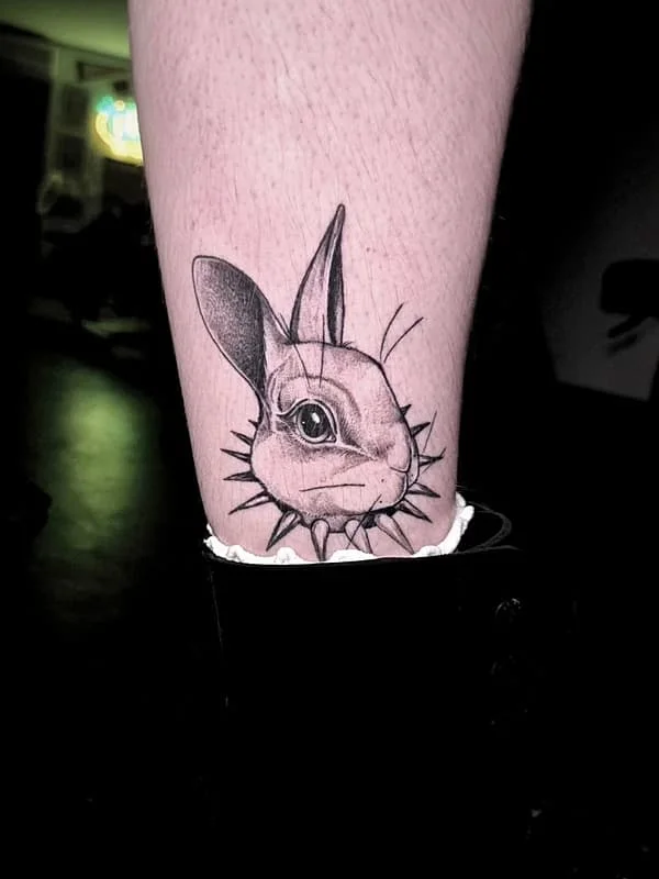 Realistic black and grey rabbit tattoo on the calf
